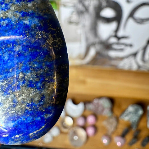 Close-up of a blue stone with a blurred background featuring a face and various objects.