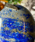 Close-up of a blue and gold marbled sphere with a silver object on top, blurred background