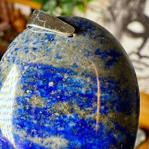 Close-up of a blue and gold marbled sphere with a silver object on top, blurred background