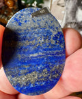 Blue stone pendant held in a hand with a blurred background