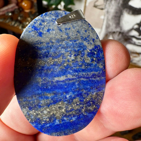 Blue stone pendant held in a hand with a blurred background