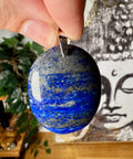 Blue stone pendant held by a hand with a blurred background