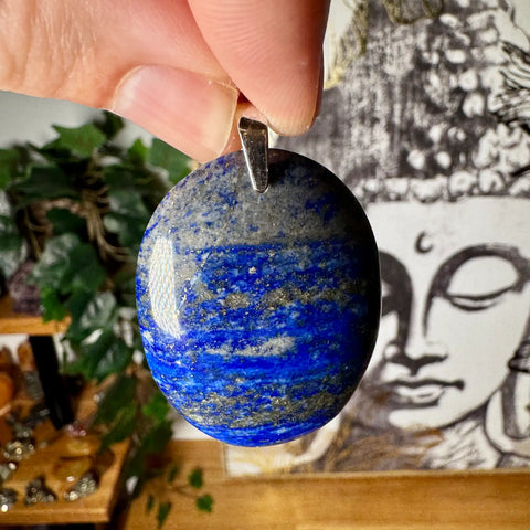 Blue stone pendant held by a hand with a blurred background