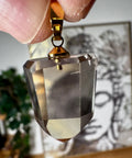 Citrine Faceted crystal pendant held by a hand with a blurred background