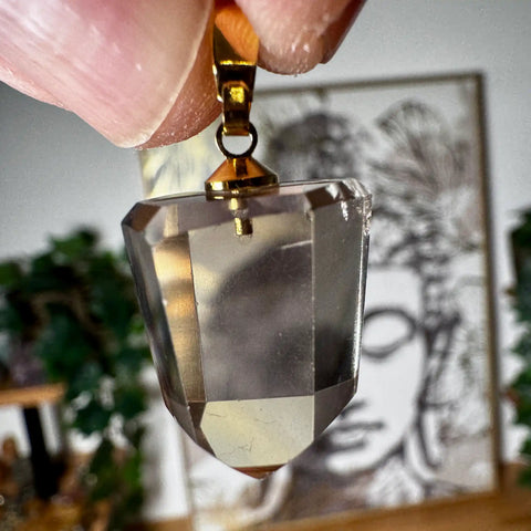 Citrine Faceted crystal pendant held by a hand with a blurred background