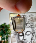 Citrine Crystal pendant held by a hand with a blurred background