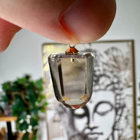 Citrine Crystal pendant held by a hand with a blurred background