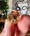 Citrine with a hexagonal top held between fingers against a blurred background