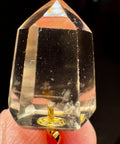 Citrine crystal held between fingers with a dark background