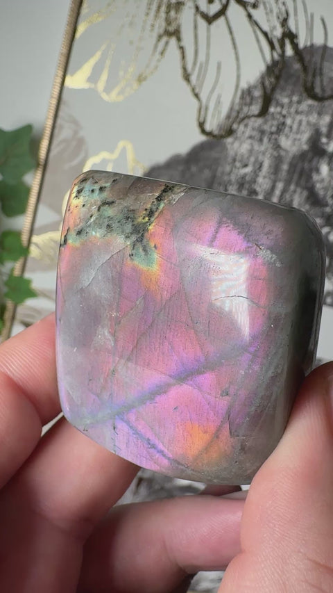 Video of Pink Labradorite freeform with purple fractures, orange glow, and gold-green shimmer – Crystals & Reiki.